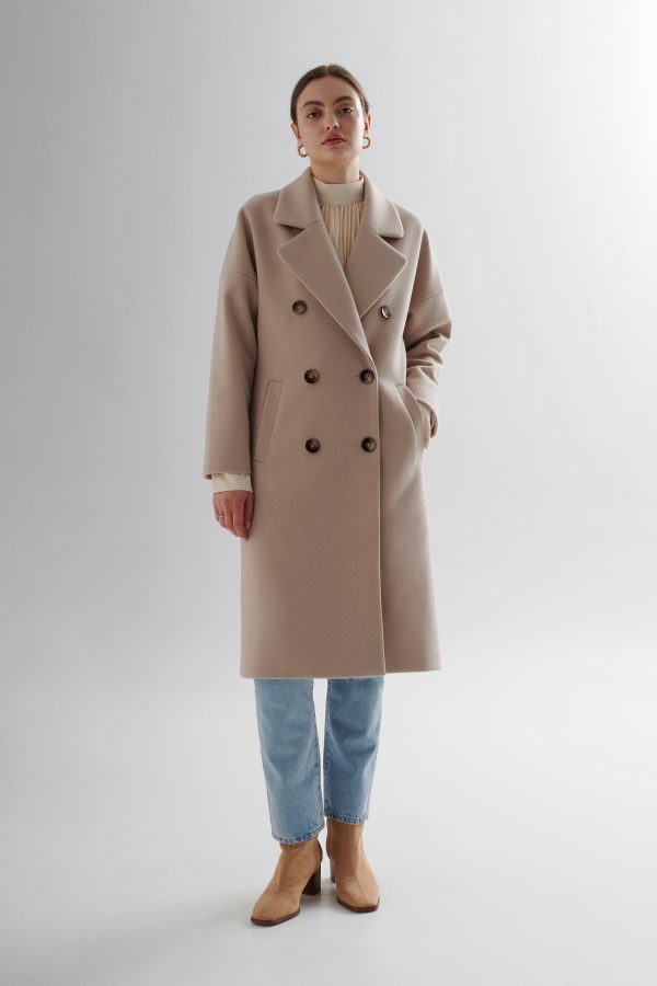 Dwurzędowy, damski płaszcz w stylu oversize w kolorze jasnego beżu.