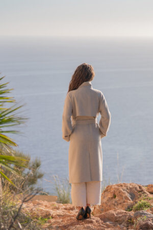 Oversizowy płaszcz typu trencz z wysokim kołnierzem i ozdobną peleryną na tyle. Wiązany i zapinany na guziki.