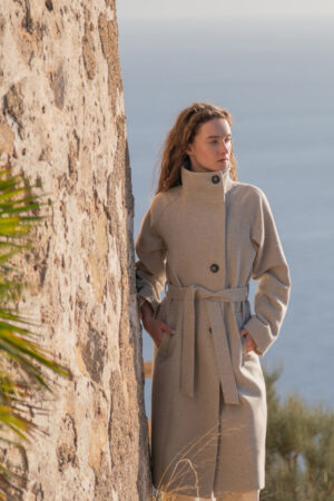 Tweedowy płaszcz trencz o długości midi. Zapinany asymetrycznie z wysokim, ozdobnym kołnierzem.