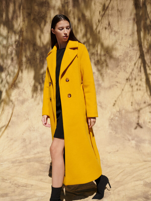 Długi zimowy płaszcz dwurzędowy w kolorze żółtym.