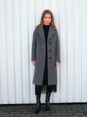 Zimowy płaszcz w luźnym kroju midi. Uszyty z mieszanki wełny. Jednorzędowy. Zapinany na guziki i wiązany.