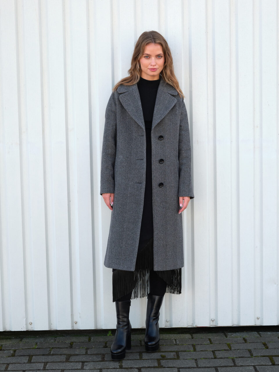 Zimowy płaszcz w luźnym kroju midi. Uszyty z mieszanki wełny. Jednorzędowy. Zapinany na guziki i wiązany.