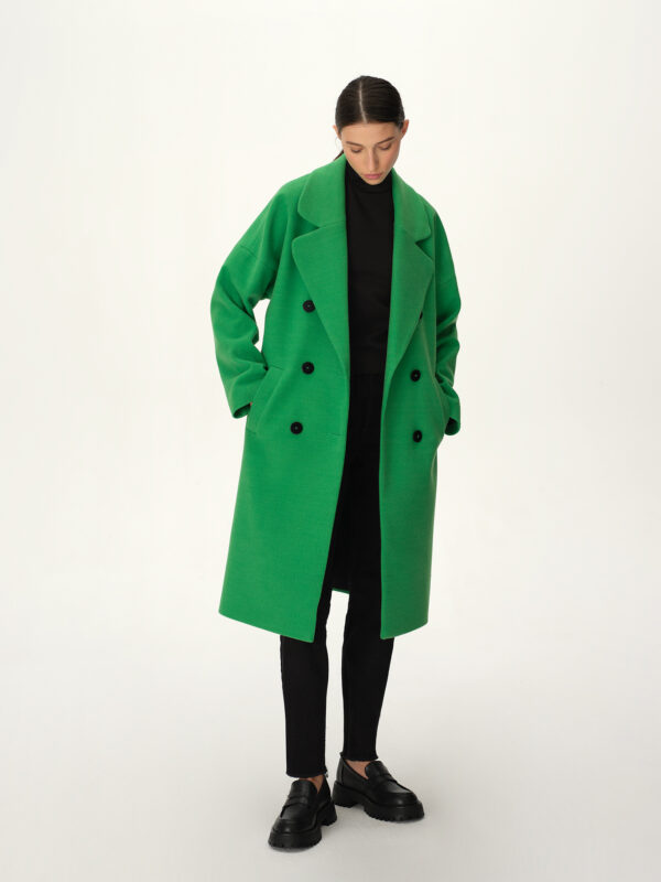 Zielony, wiosenny płaszcz w stylu oversize z czarnymi guzikami i szerokim kołnierzem.