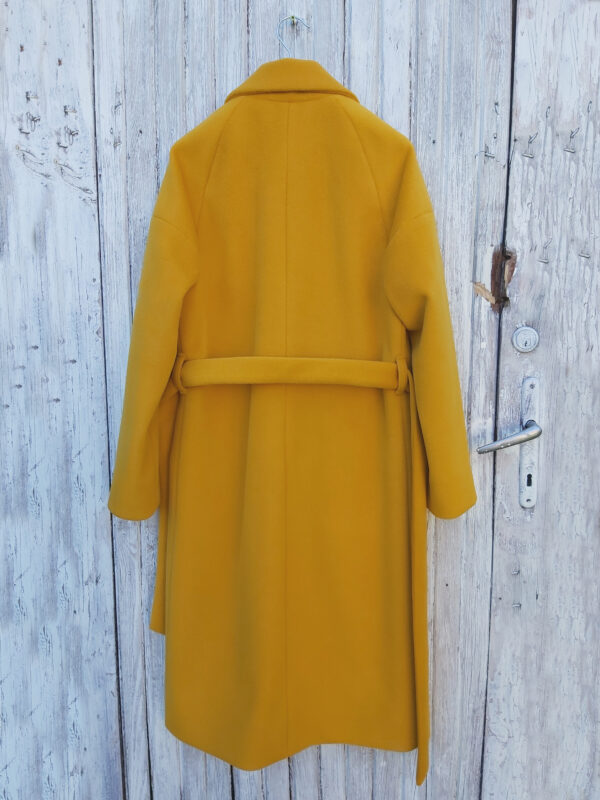 Żółty zimowy płaszcz o luźnym kroju z raglanowymi rękawami zapewniającymi komfort. Wiązany. Uszyty z miękkiego materiału. Dodatkowo ocieplany.