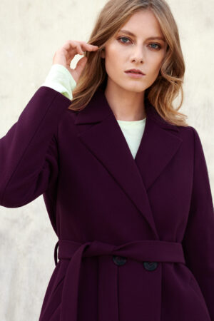 Klasyczny płaszcz z kołnierzem typu rewers w burgundowym kolorze. Wiązany w pasie. Długość w kolano.