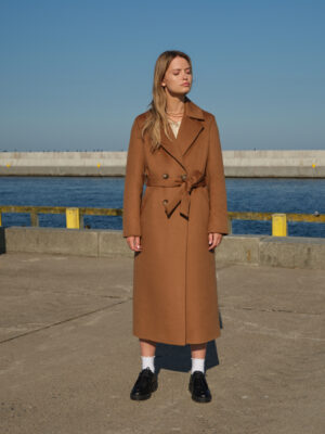 Camelowy długi płaszcz z wełny wielbłądziej o szlafrokowym kroju. Wiązany w pasie, zapinany na guziki. Uszyty z szlachetnej tkaniny o falistej strukturze, efekt zibellino.