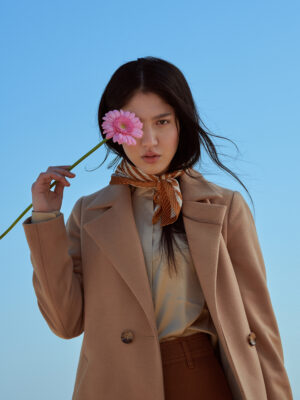 Camelowy płaszcz zapinany na guziki z kołnierzem typu rewers.