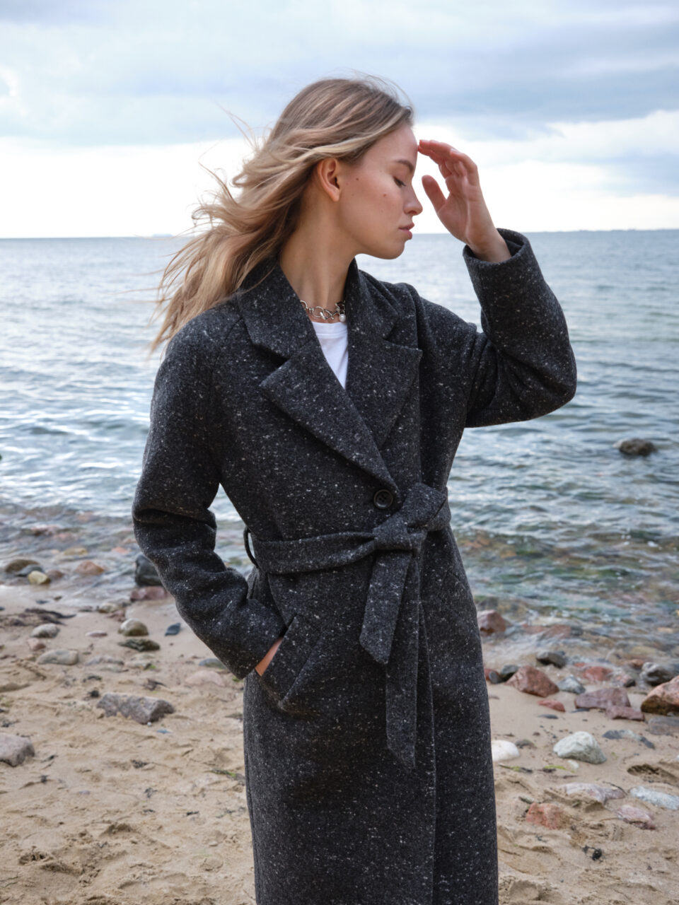 Czarny melanżowy płaszcz wełniany z mięsistego materiału. Jednorzędowy, zapinany na guziki. Wiązany w pasie. Idealnie sprawdzi się zimą. Ocieplany.