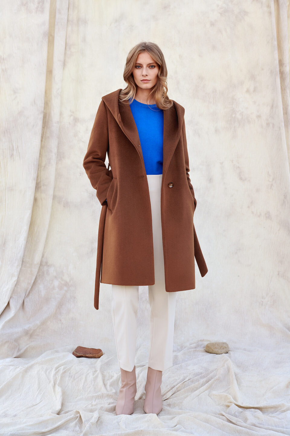 ZImowy płaszcz damski z kapturem w kolorze koniakowym, zapinany na guziki.