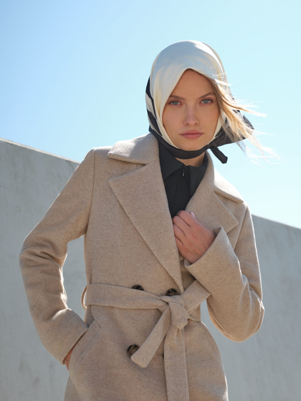 Długi beżowy płaszcz zimowy z wełnianej mieszanki. Zapinany na guziki i wiązany w pasie. Minimalistyczny. Idealna baza dla wielu stylizacji. Szykowny i ciepły.