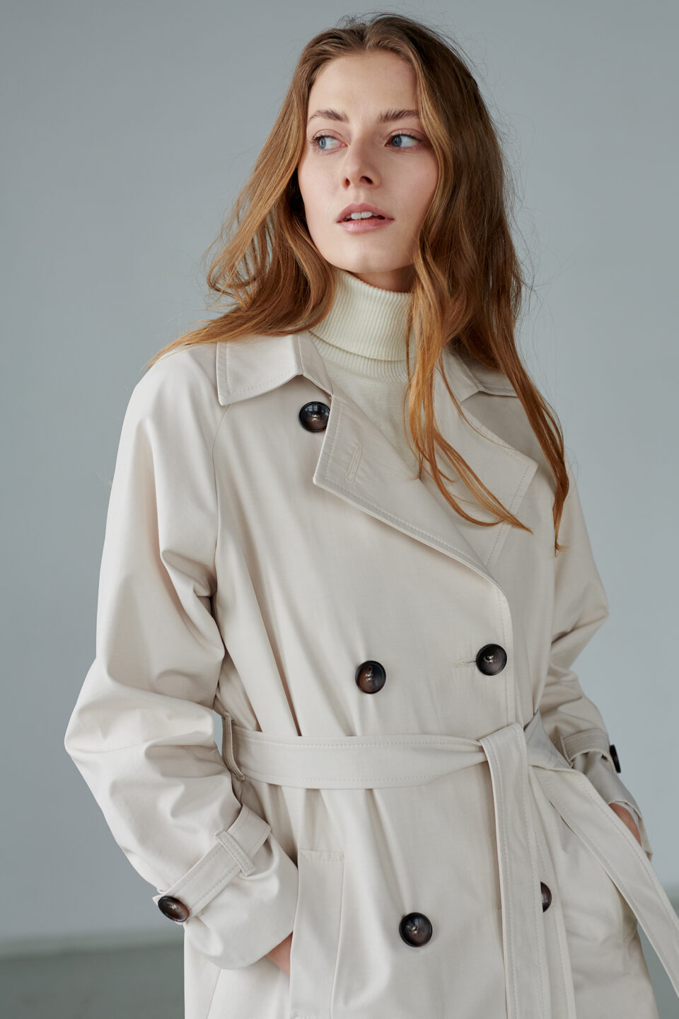Długi płaszcz trenczowy z peleryną na tyle, obszerny, oversizowy, wiązany i zapinany na guziki.