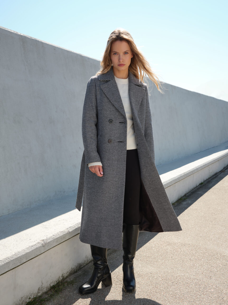 Długi zimowy płaszcz damski w czarno-białą jodełkę. Uszyty w wełny dziewiczej. Klasyczny krój i ponadczasowy wzór. Wygodny, elegancki. Idealny do warstwowych zestawów. Na lata.
