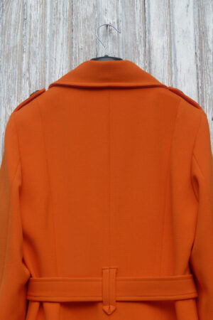 Tył płaszcza w stylu trencza w kolorze pomarańczowym.