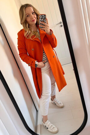 Klasyczny dwurzędowy trencz wiosenny w pomarańczowym kolorze.