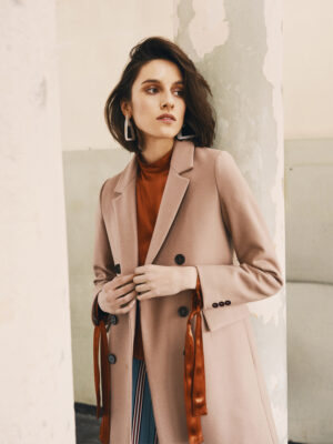 Płąszcz damski w kolorze jasny kamel z guzikami i kołnierzem typu rewers.