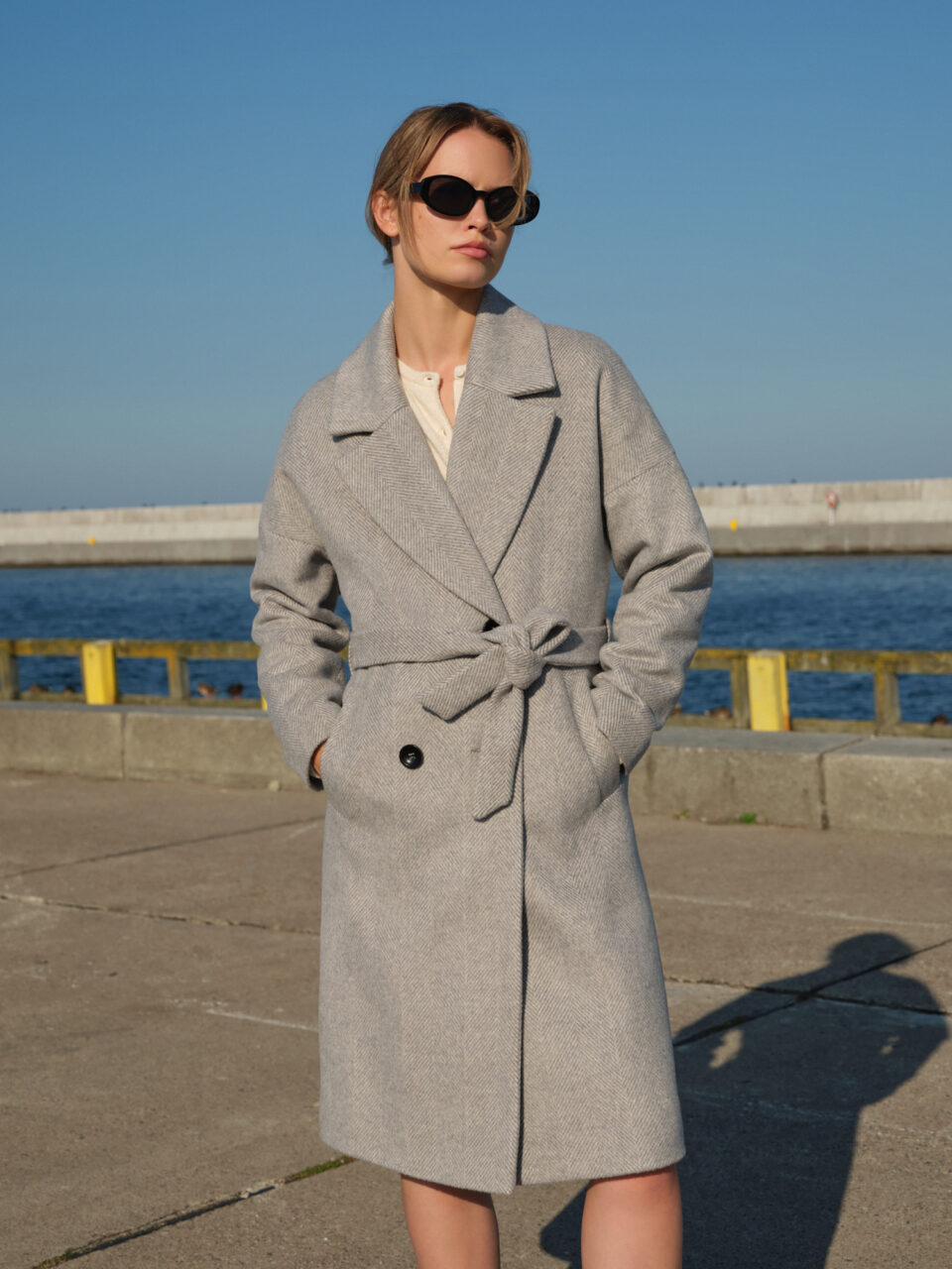 Oversizowy płaszcz damski zimowy o obniżonej linii ramion. Pudełkowy krój z kołnierzem z klapami w stylu vintage. W ponadczasową jodełkę w stonowanej kolorystyce. Klasyka w nowoczesnej odsłonie.