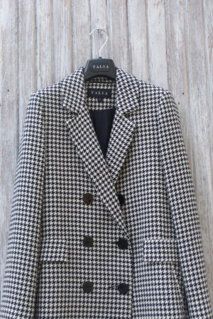 Dwurzędowa marynarka w pepitkę czano-białą zapinana dwurzędowo z ozdobnymi patkami na froncie.