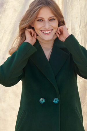 Zimowy płaszcz damski w kolorze butelkowej zieleni, zapinany na guziki.