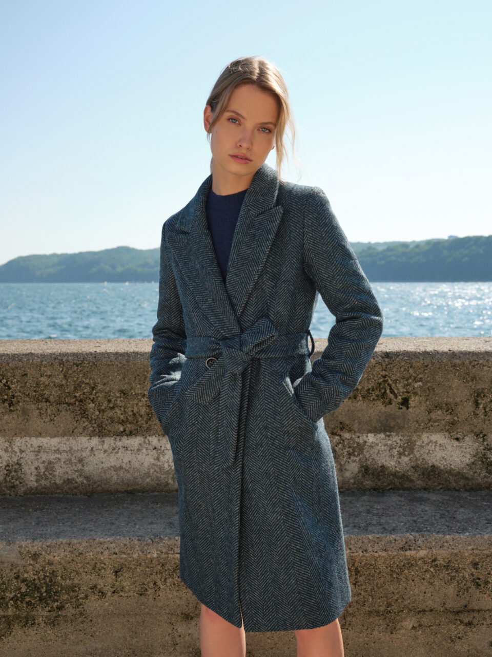 Płaszcz taliowany zimowy z wełny dziewiczej z paskiem. Minimalistyczny krój, miękki i ciepły materiał, klasyczny wzór jodełki. Otula i dodaje szyku. Utrzymany w duchu slow.