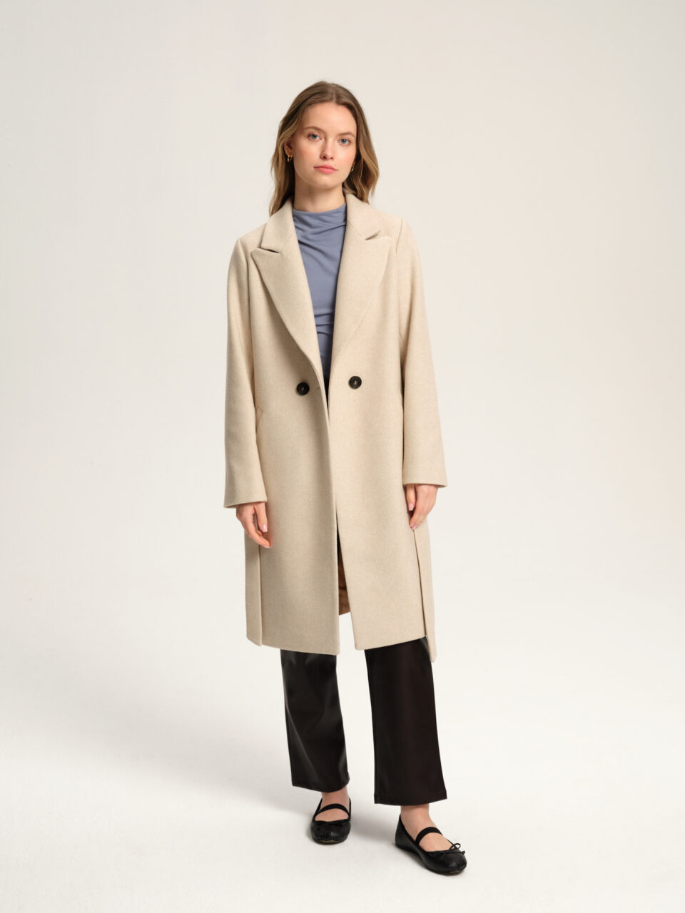 Klasyczny płaszcz damski o taliowanym kroju. Długość w kolano. Wykładany kołnierz typu rewers. Zapinany na guziki i wiązany w pasie. Uszyty z pięknej mieszanki wełny i podszewki acetatowej. Idealny na przejściowe pory roku. Materiał w ciekawy wzór.