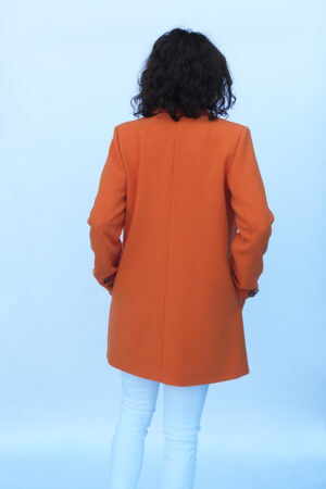 Wiosenny płaszczyk damski w kolorze pomarańczowym o prostym, marynarkowym kroju.
