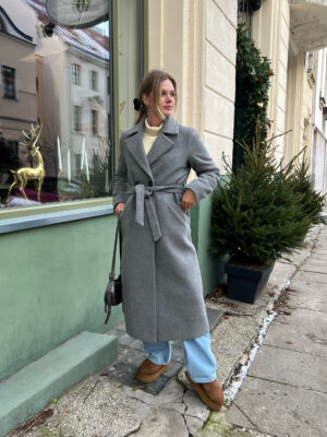 Szary wełniany płaszcz zimowy o szlafrokowym kroju. Taliowany tył, profilowany przód i dodatkowo wiązany. Długość do połowy łydki.