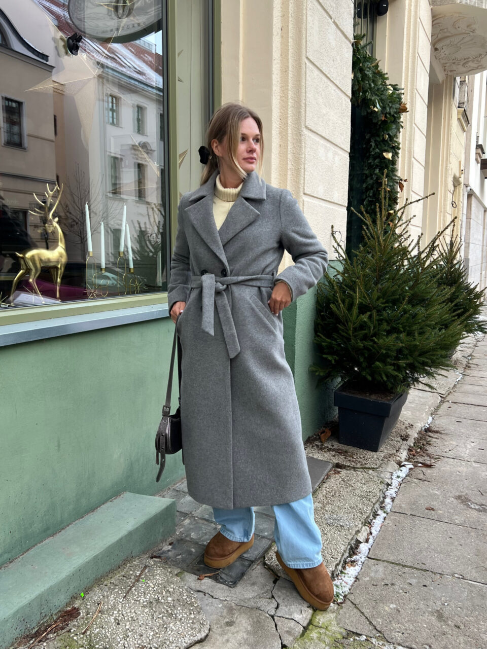 Szary wełniany płaszcz zimowy o szlafrokowym kroju. Taliowany tył, profilowany przód i dodatkowo wiązany. Długość do połowy łydki.