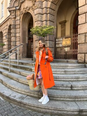 Trencz damski o klasycznym kroju. Zapinany dwurzędowo na guziki. Dopasowany do sylwetki. Wiązany w pasie. Delikatnie rozkloszowany ku dołowi.