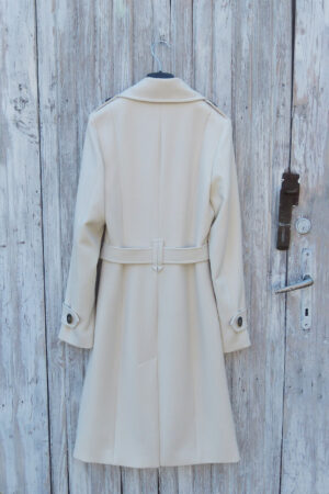 Prochowiec trencz w kolorze śmietankowym z rozporkiem z tyłu z guzikami na mankietach.