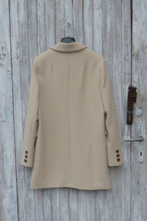 Luźny, krótki trencz wiosenny z ozdobnymi guziczkami na mankietach.