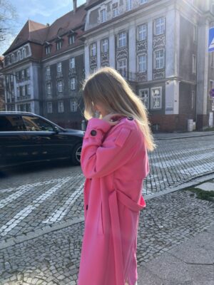 Trencz damski wiosenny w oversizowym stylu. Wiązany w pasie. Kołnierz rewers z klapami otwartymi. Ozdobna peleryna na tyle. Ponadczasowa klasyka. Polskie rzemiosło i ręcznie szyte płaszcze damskie.