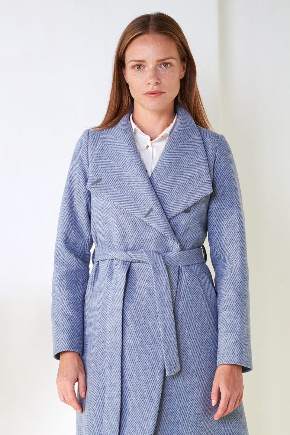 Wysoko zapinany płaszcz zimowy w jodełkę. Zapinany na 3 guziki - wtedy tworzy małą otulającą stójkę. Rozpięty kołnierz układa się w szpic. Asymetryczny przód. Wełniany.