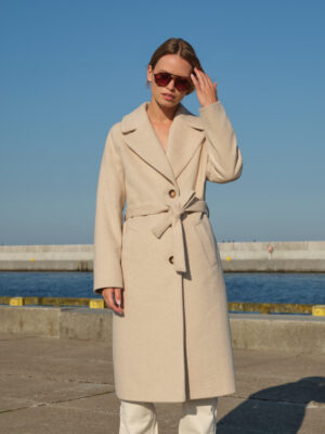 Zimowy, jednorzędowy płaszcz w beżową jodełkę z raglanowymi rękawami. Wiązany w pasie, zapinany na guziki. Klasyczny krój, świetny jakościowo materiał, ponadczasowy wzór jodełki. Utrzymany w trendzie Quiet Luxury.