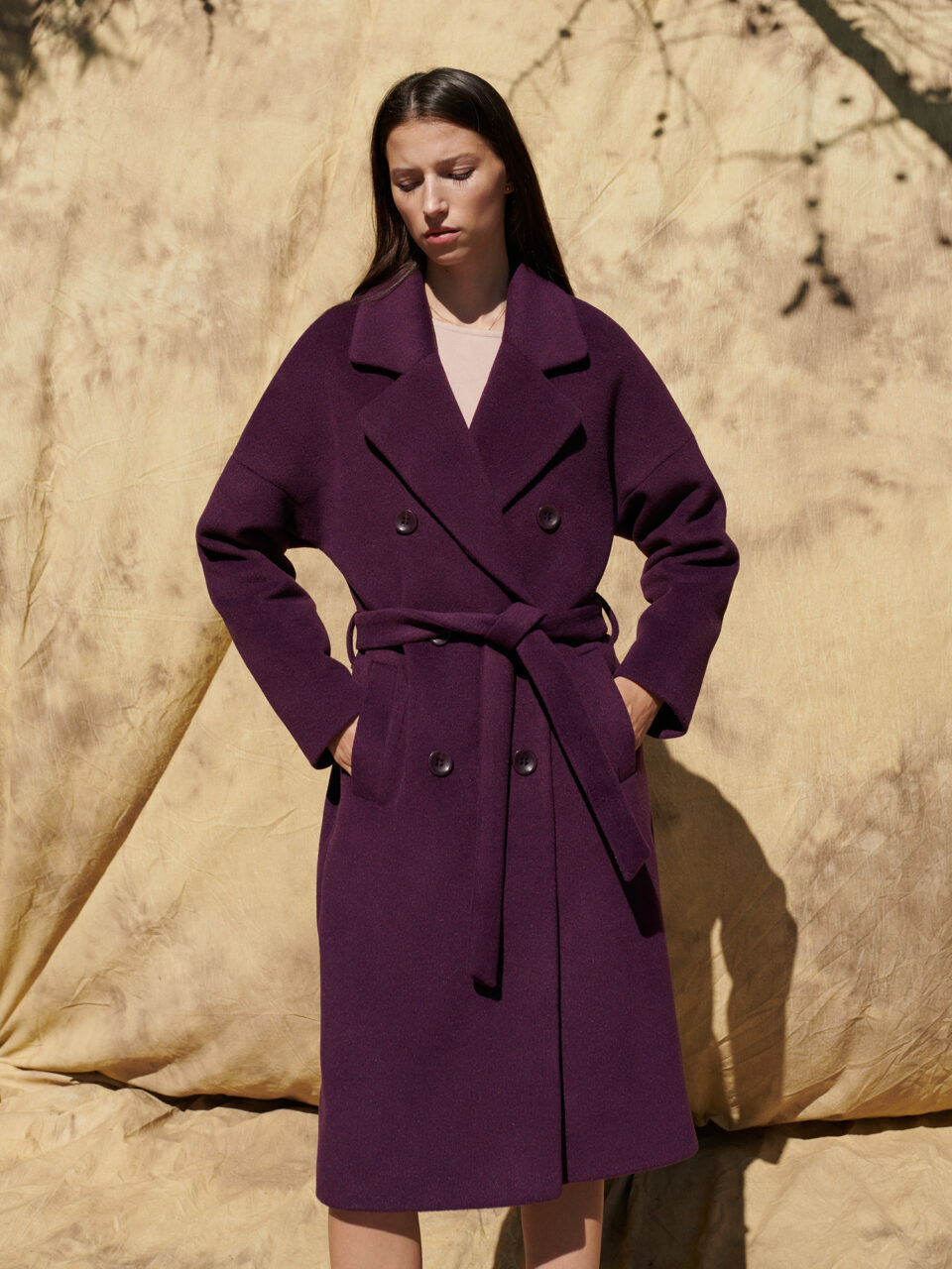 Zimowy płaszcz wełniany w oversizowym stylu zapinany na guziki i wiązany w pasie.