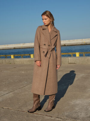 Brązowy płaszcz damski zimowy z wełny z delikatnym włosem, dodającym miękkości i przytulności. Kołnierz z klapami typu rewers. Zapinany dwurzędowo na guziki. Wiązany w pasie. Długi z rozporkiem na tyle.