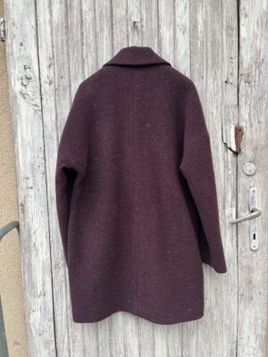 Burgundowy plaszczyk do połowy uda. Zapinany dwurzędowo. Swobodny i bardzo wygodny krój. Uszyty z wełny dziewiczej i kaszmiru.