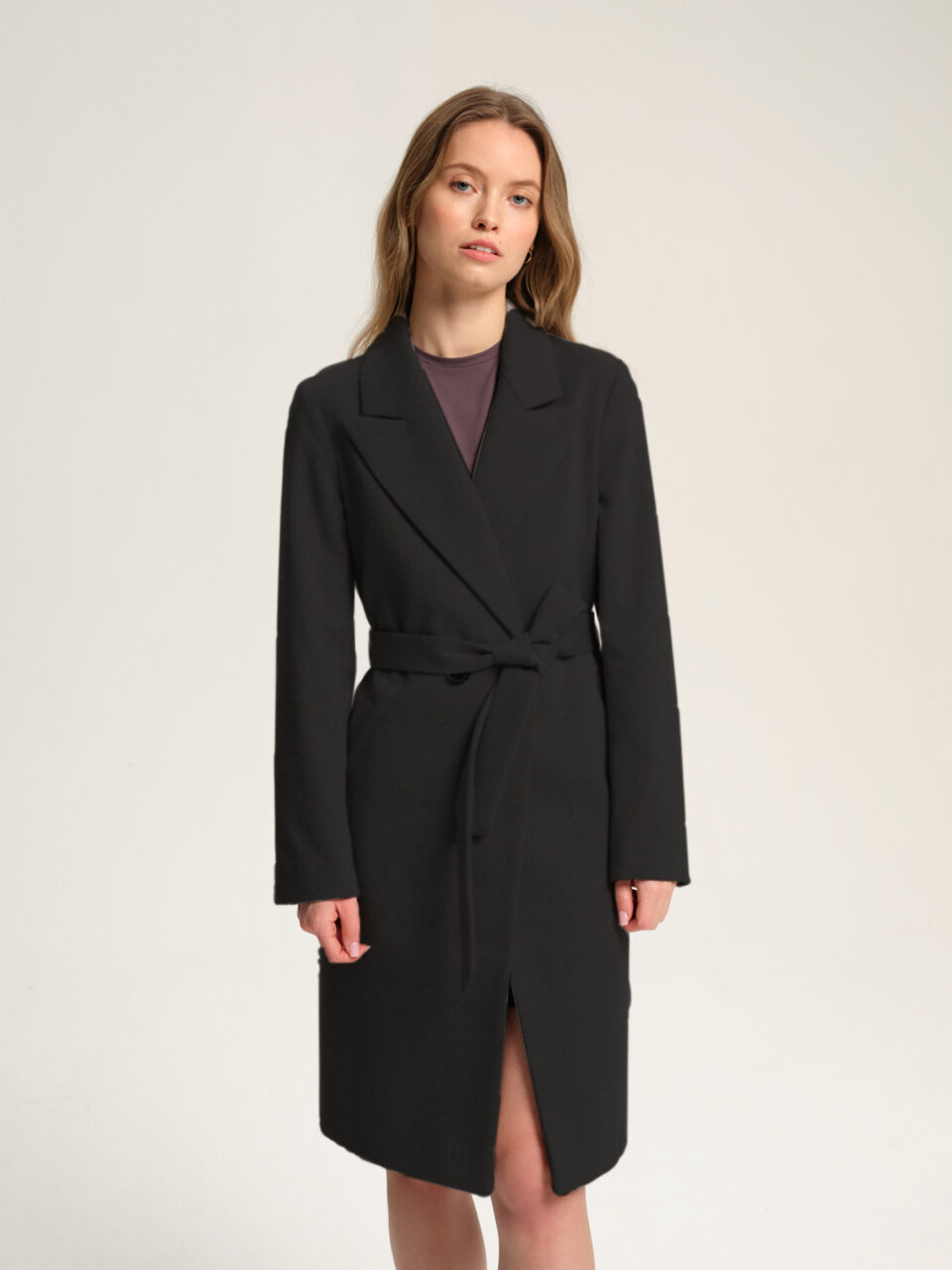 Czarny płaszczyk przejściowy w kolano z paskiem. Uszyty z lżejszej wełny. Klasyczny krój i uniwersalny kolor.