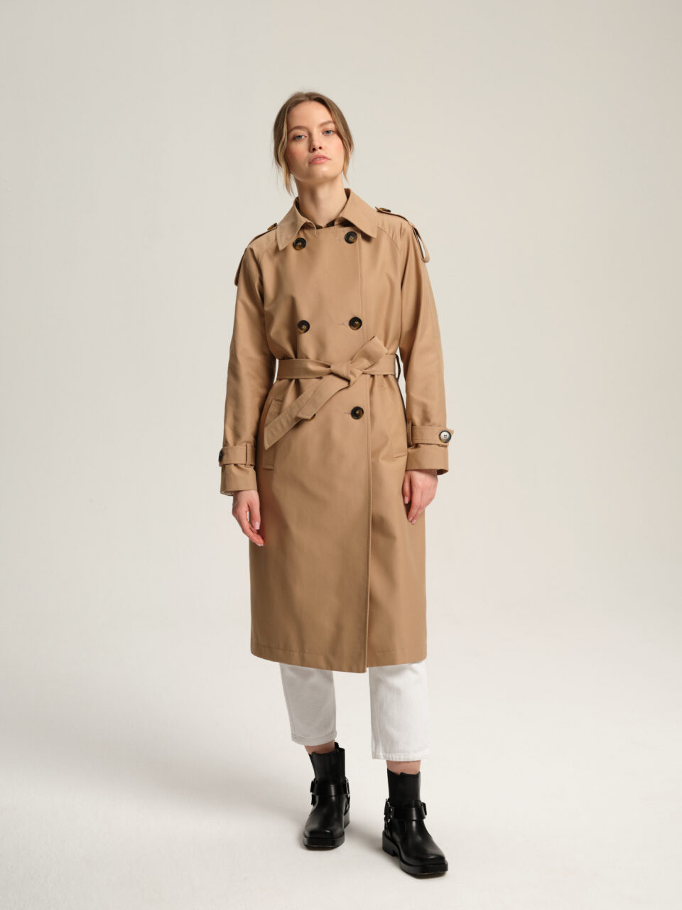 Długi trencz damski w luźnym stylu z tkaniny bawełnianej z powłoką hydrofobową w ciepłym, beżowym kolorze.