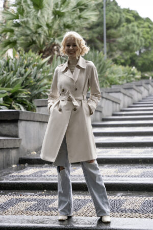 Dwurzędowy trencz damski o klasycznym taliowanym kroju. Uszyty z tkaniny bawełnianej pokrytej powłoką hydrofobową.