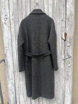 Grafitowy płaszcz w jodełkę w oversizowym stylu zapinany dwurzędowo i wiązany w pasie.