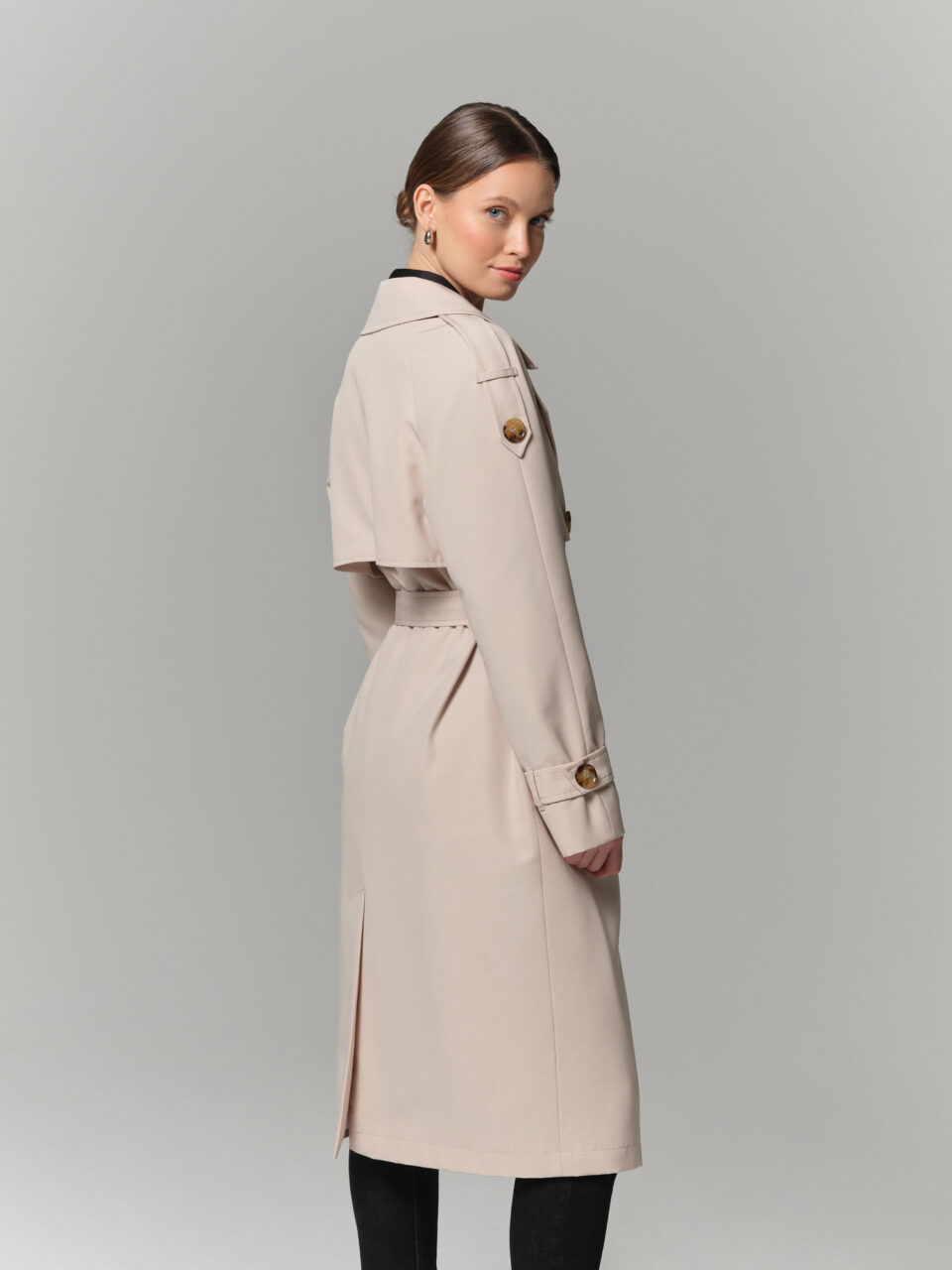 Kremowy trencz z mieszanki bawełny pokrytej hydrofobową powłoką. Raglanowy rękaw, kołnierz rewers i peleryna.