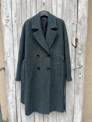 Klasyka z twistem. Oversizowy wełniany płaszcz zimowy w jodełkę. Zapinany dwurzędowo i wiązany w pasie. Ocieplany.