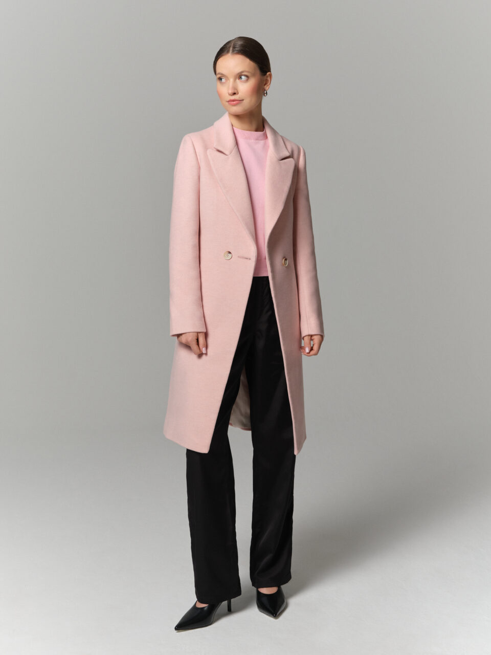 Płaszczyk damski o długości w kolano. Zapinany na guzik i wiązany. Uszyty z pięknej wełny w pastelowym różowym kolorze.