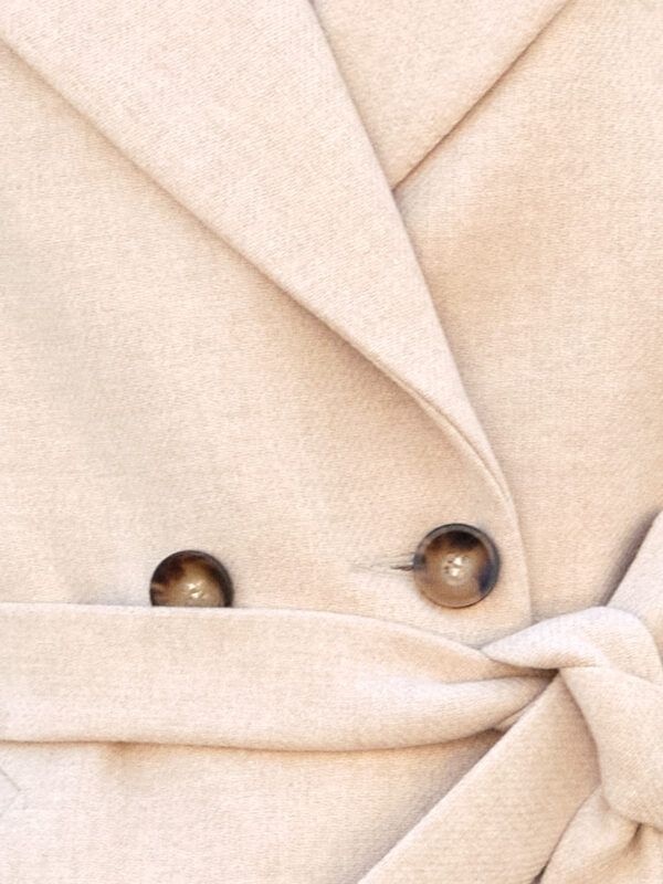 Kremowo-beżowy wełniany materiał z fakturą.