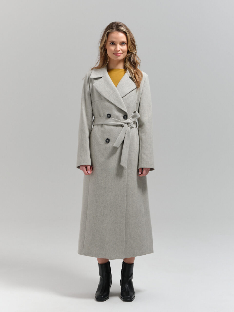 Długi płaszcz damski z wełnianego tweedu w jasnoszarym odcieniu wpadajacym w biel. Dopasowany krój z dwoma rozporkami.