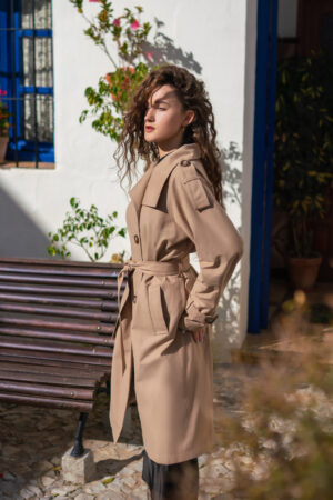 Długi beżowy trencz w stylu oversize z peleryną na tyle. Podpinany, wysoki kołnierz. Idealny na wiosnę i jesień.