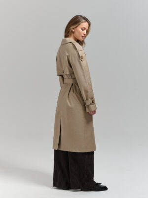 Klasyczny trencz damski o nowoczesnym, swobodnym kroju. Raglanowy rękaw, pagony, peleryna na plecach. Zapinany dwurzędowo. Wiązany.