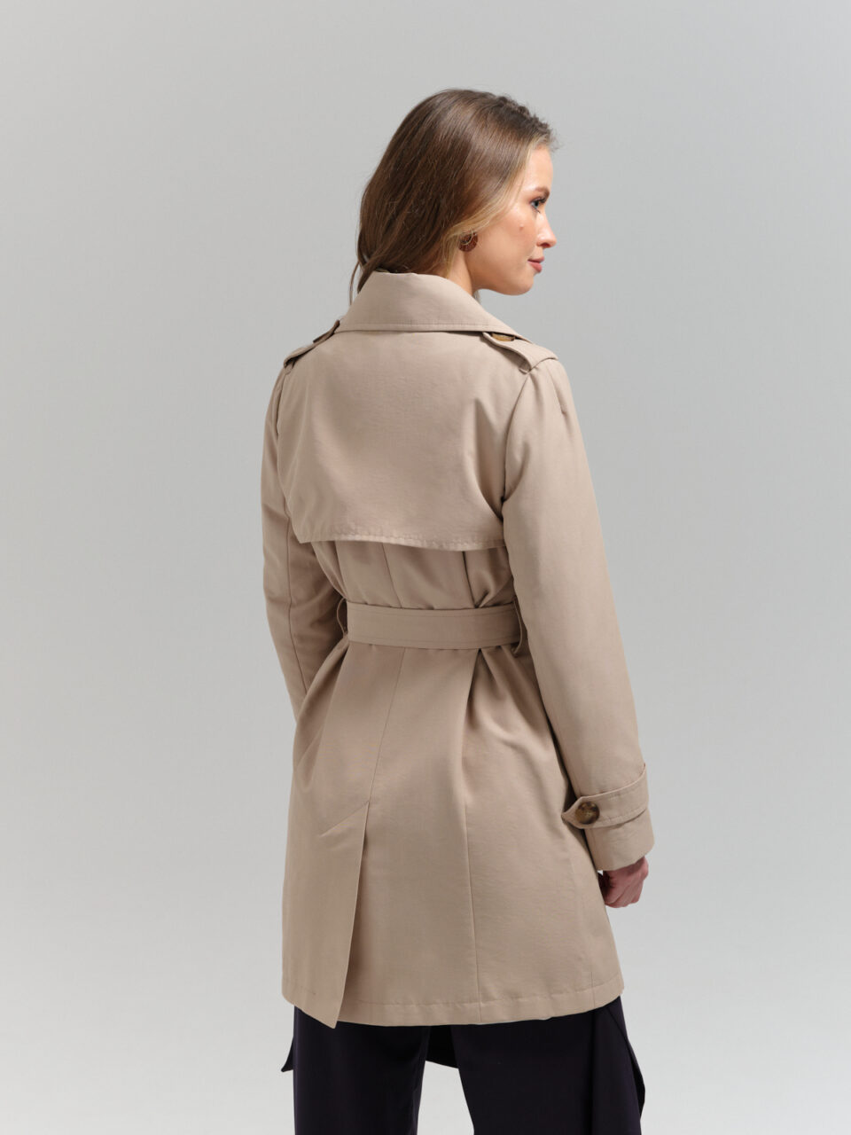 Krótki bawełniany trencz damski o dopasowanym kroju do połowy uda w beżowym kolorze.